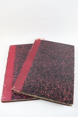 deux cahiers rouges posés l'un sur l'autre sur une surface blanche