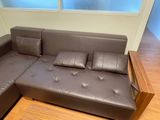 a brown leather couch with pillows on it in a living room