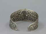 a close up of a silver bracelet on a gray surface