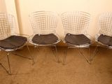 quatre chaises en acier chromé avec des coussins d'assise noirs dans une pièce