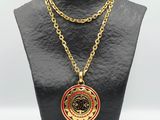 un collier en or orné d'un médaillon rouge sur un mannequin noir