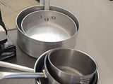 des casseroles et des poêles sont posées sur une table dans une cuisine