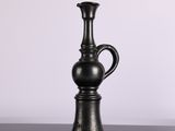 a black vase sitting on a table with a white background