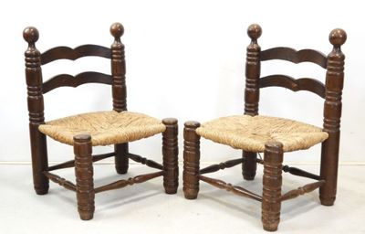 pair of wooden chairs with wicker seats against a white wall