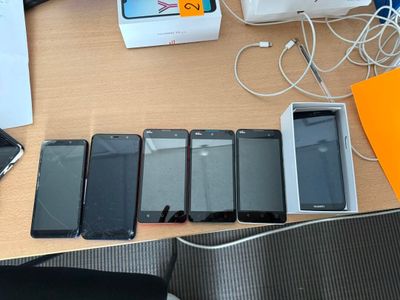Plusieurs téléphones portables sont alignés sur une table à côté d'un ordinateur portable
