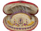 une image représentant un coffret à bijoux rouge et or orné de pierres précieuses violettes