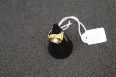 a gold ring with a pearl in it on a black surface