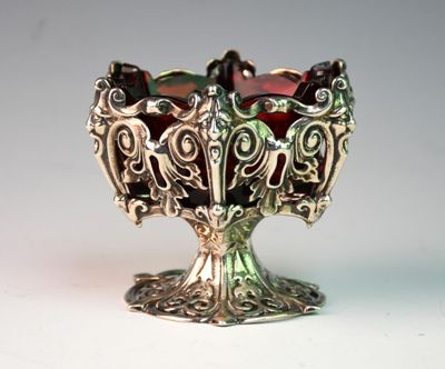 a silver bowl with a red glass inside of it