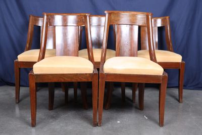three wooden chairs with beige upholstered seats against a blue backdrop