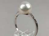 an image of a pearl and diamond ring sitting on top of a clear surface