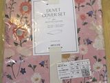 pink floral bedding set in plastic bag on wooden floor