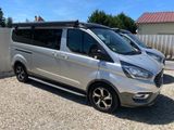 La camionnette argentée est garée sur le gravier, près d'une clôture.