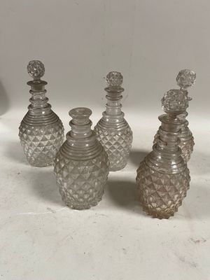 quatre bouteilles en verre ornées de nombreux petits motifs, posées sur une table
