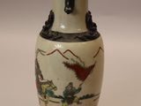 a white vase with a painting on it sitting on a table