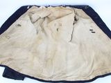 a tan jacket with black trim on a white surface