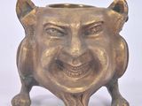 a small gold pot with a smiling face on it