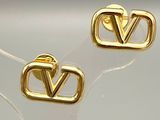 paire de boucles d'oreilles clous plaquées or en forme de « V » sur un fond transparent