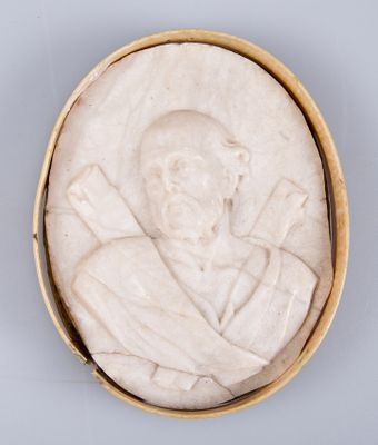 un gros plan sur une plaque en pierre blanche représentant un homme coiffé d'un chapeau