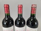 three bottles of red wine sitting on top of a white table