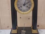 une horloge noire et dorée posée sur une table en marbre