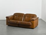 a brown leather couch in a room with a white wall