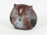 a small owl figurine sitting on a white surface