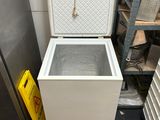 a white chest freezer sitting in a kitchen next to a metal rack