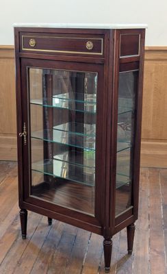 a display cabinet with a glass door in the middle of the room