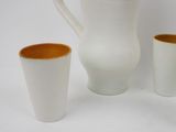 three cups and a pitcher sitting next to each other on a table