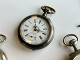 three different types of pocket watches on a white surface