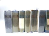 several books are lined up in a row on a white surface