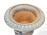 a metal vase that has a brown substance in it