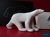 une petite figurine d'ours polaire blanc posée à côté d'une boîte