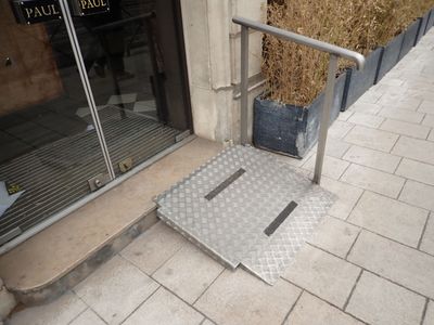 une rampe métallique sur le trottoir, à côté d'un immeuble
