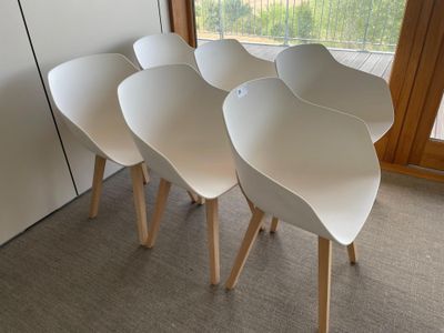 four white chairs sitting next to each other in front of a window