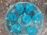 une assiette en verre posée sur une table, sur laquelle se trouvent des tasses bleues