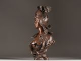 bronze bust of a woman with long hair and a bow on her head