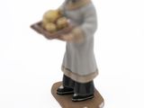 a figurine of a man holding a tray of potatoes