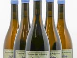 quatre bouteilles de vin sont alignées sur une surface blanche