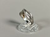 une bague en argent sertie d'un diamant, posée sur un socle transparent