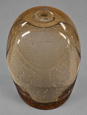une image représentant un vase en verre brun posé sur une surface grise