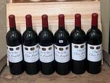 six bottles of red wine are lined up in front of a wooden crate