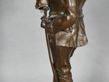 bronze figurine of a man holding a bird on a pedestal