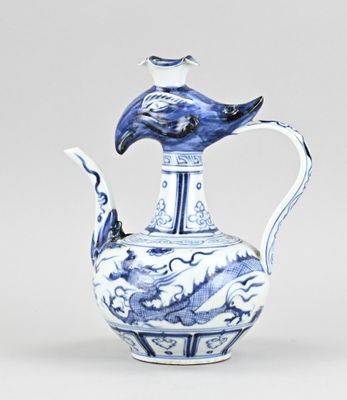 un vase bleu et blanc surmonté d'un oiseau