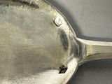 a silver spoon with a hole in it on a table