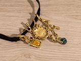 a black cord with a gold necklace on it on a wooden surface