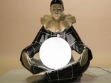 a figurine of a woman sitting in a lotus pose with a glowing ball in her hands