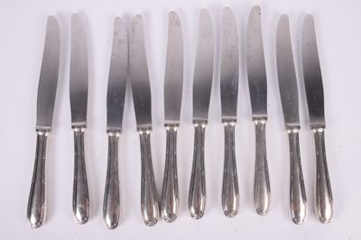 six silverplated knives are lined up on a white surface