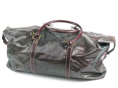 un sac de voyage en cuir marron posé sur une surface blanche