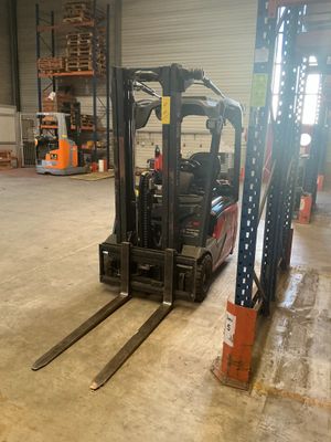 a forklift in a large warehouse with lots of pallets